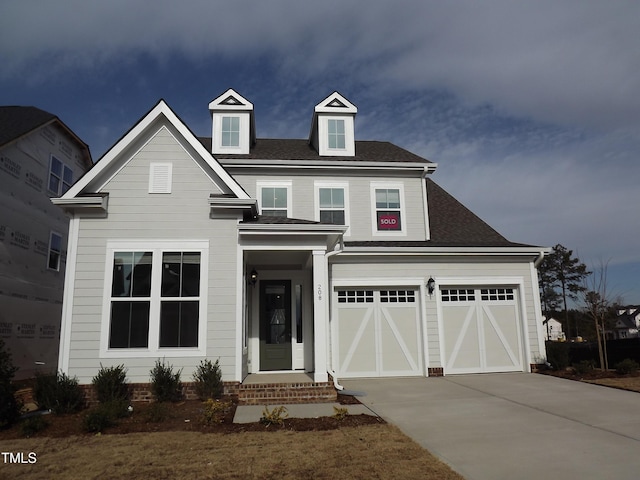 view of front of home featuring driveway, a shingled roof, and an attached garage