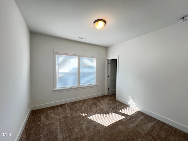 carpeted spare room featuring visible vents and baseboards