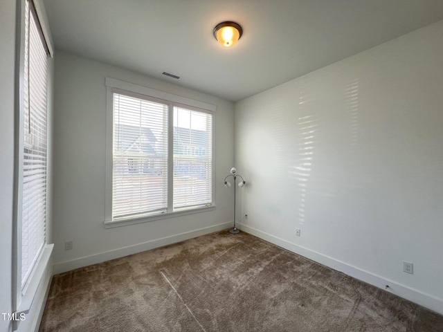 empty room featuring visible vents, baseboards, and carpet floors