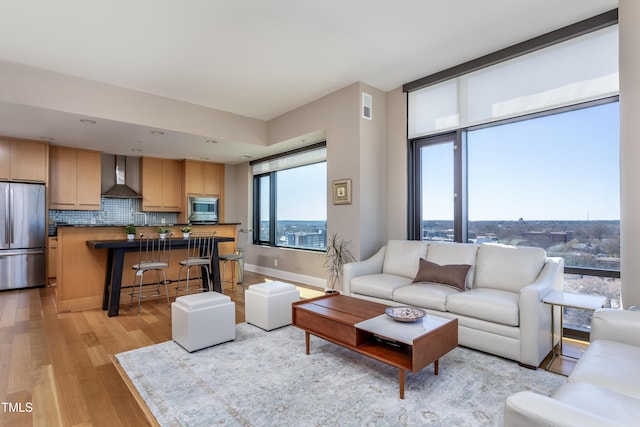 living area with visible vents, baseboards, and light wood finished floors