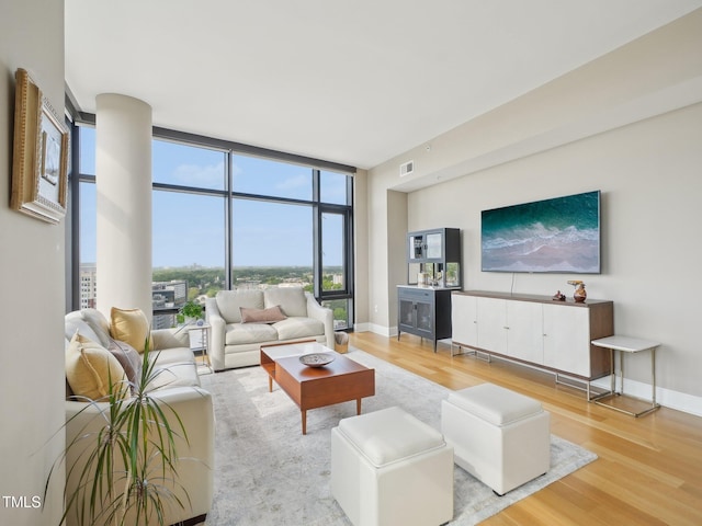 living area featuring baseboards, floor to ceiling windows, wood finished floors, and visible vents