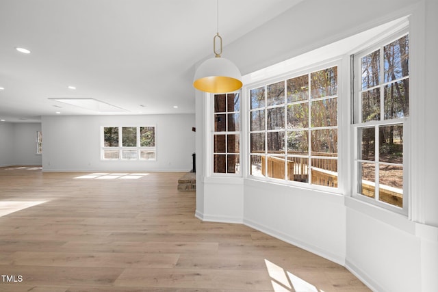 unfurnished dining area featuring a skylight, recessed lighting, light wood-style floors, and baseboards