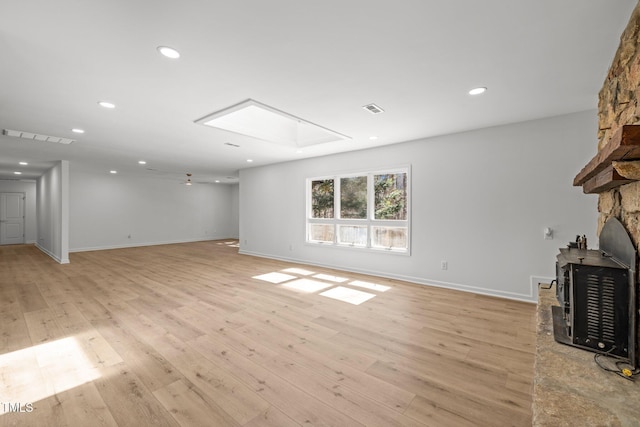 unfurnished living room with recessed lighting, visible vents, light wood-style flooring, and a wood stove