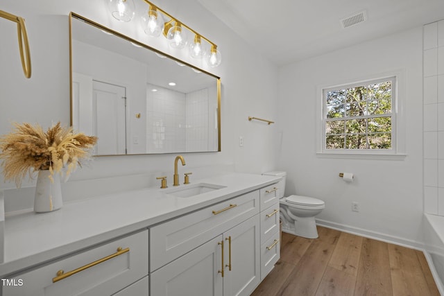 bathroom with vanity, wood finished floors, visible vents, a shower, and toilet