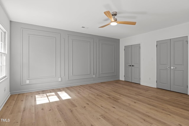 unfurnished bedroom featuring baseboards, multiple windows, two closets, and light wood-style floors