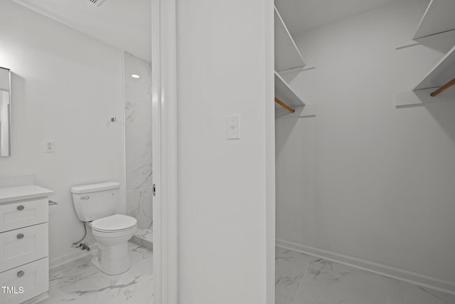 bathroom with vanity, toilet, baseboards, and marble finish floor