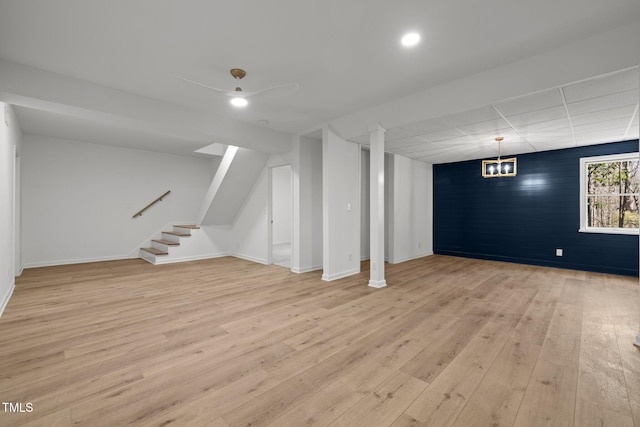 basement with a drop ceiling, stairway, baseboards, and light wood-style flooring