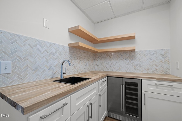 kitchen featuring backsplash, open shelves, beverage cooler, butcher block counters, and a sink