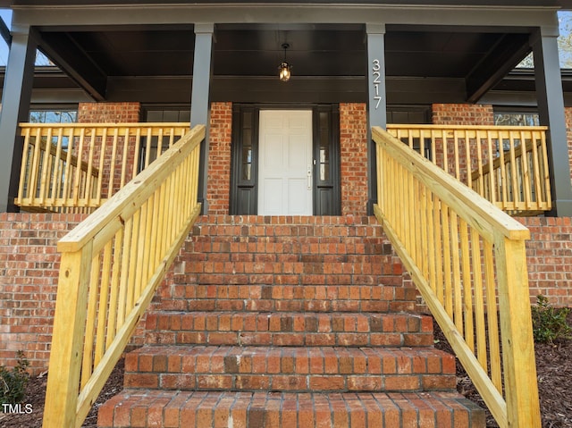 property entrance featuring brick siding and covered porch