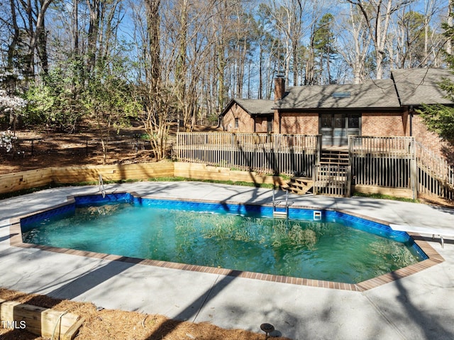 view of pool featuring a diving board, a fenced in pool, a patio, and a deck