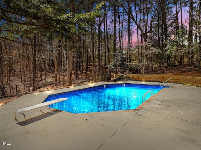 pool at dusk featuring a fenced in pool and a patio