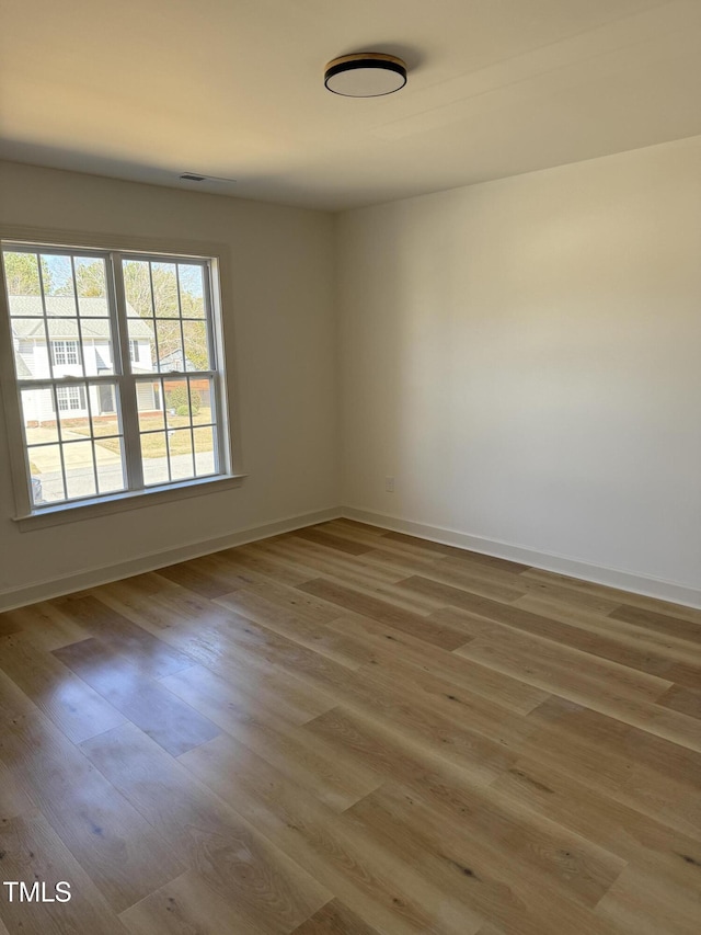 spare room with baseboards and wood finished floors