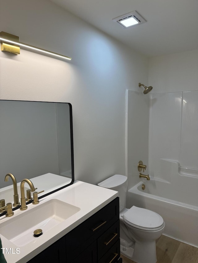 bathroom with visible vents, toilet, wood finished floors, shower / bathing tub combination, and vanity