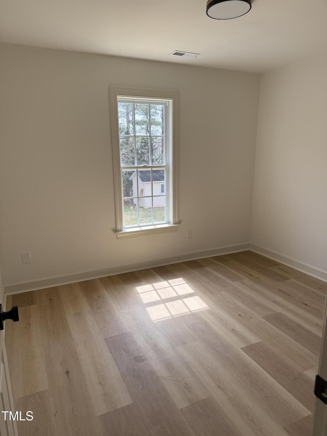 unfurnished room with visible vents, light wood-style flooring, and baseboards