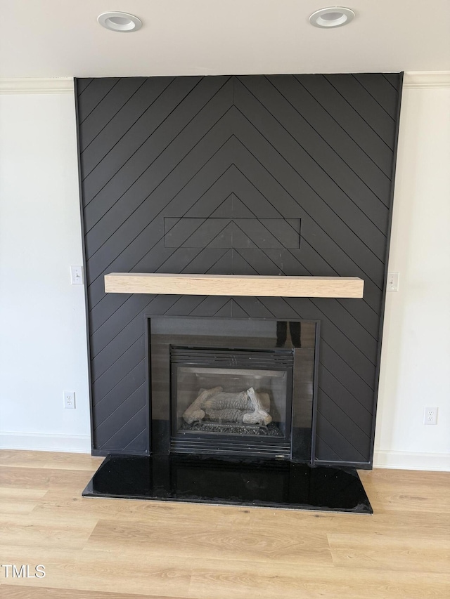 interior details with baseboards, a large fireplace, and wood finished floors