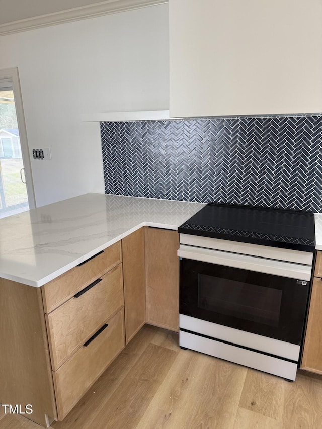 kitchen featuring light stone counters, a peninsula, electric range, decorative backsplash, and light wood-style floors