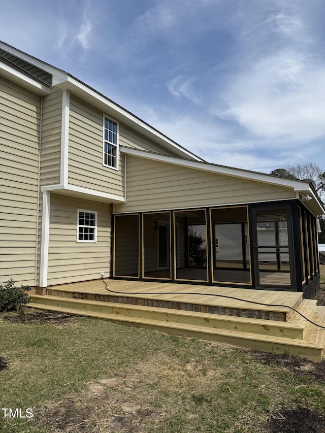 back of property featuring a sunroom and a wooden deck