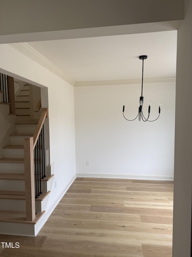 interior space featuring light wood finished floors, crown molding, baseboards, a chandelier, and stairway