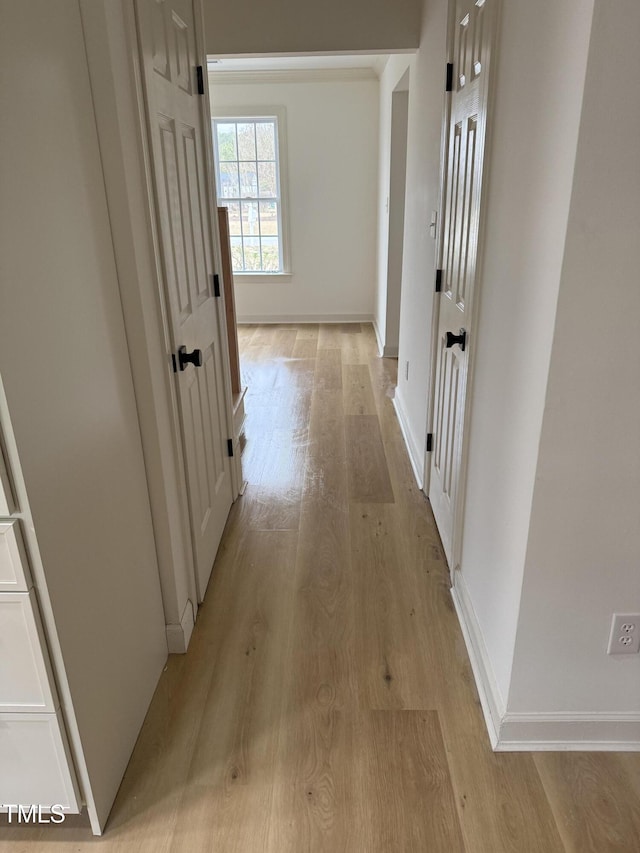 hallway with light wood-type flooring and baseboards