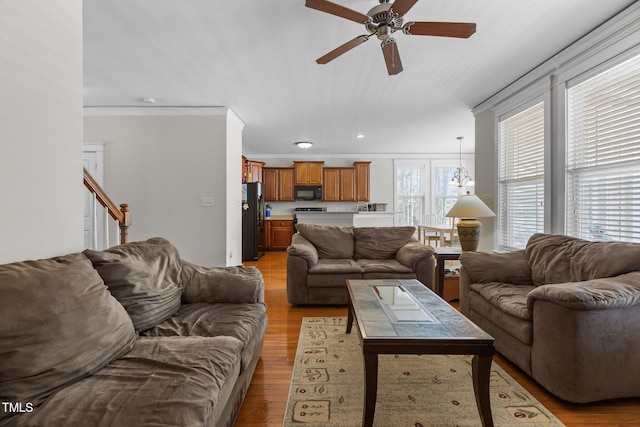 living room featuring crown molding, ceiling fan, stairs, recessed lighting, and light wood-style floors