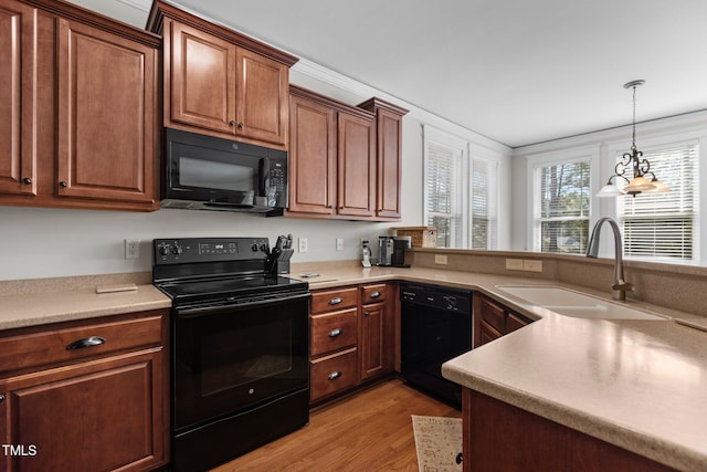 kitchen with black appliances, light countertops, light wood finished floors, and a sink