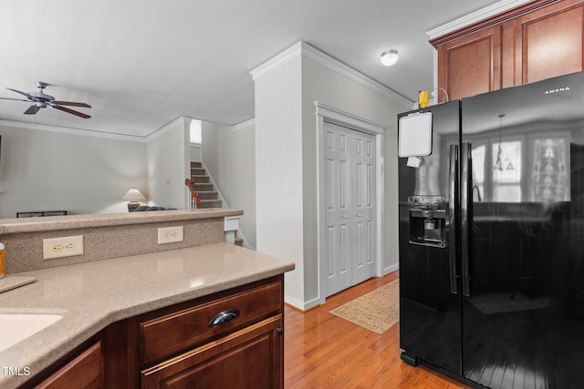 kitchen with ceiling fan, light wood-type flooring, ornamental molding, black fridge, and a sink