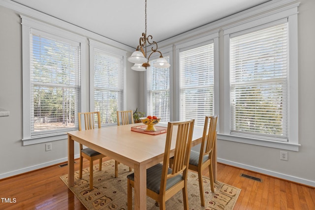 dining room featuring baseboards, light wood-style floors, visible vents, and a chandelier