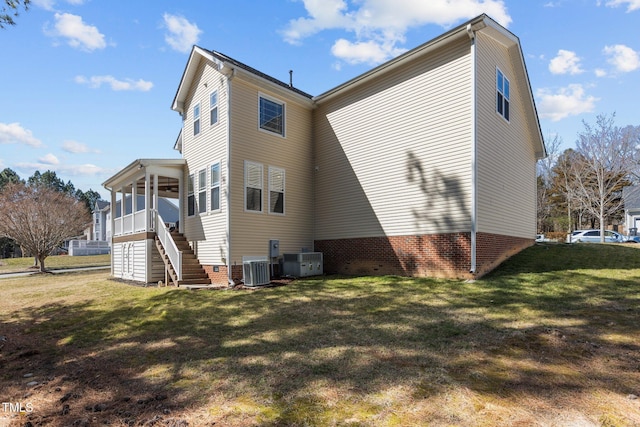 rear view of house featuring central AC unit, a lawn, and stairs