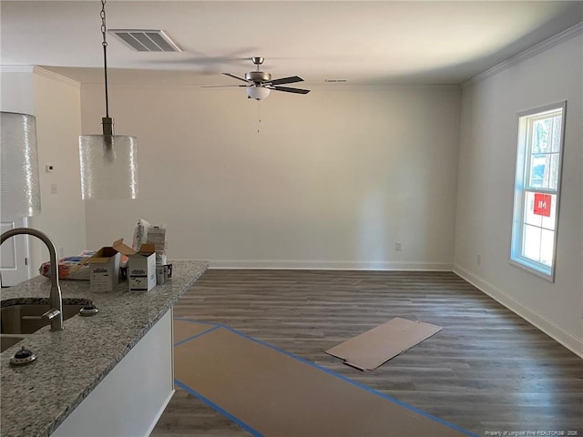 spare room with a ceiling fan, a sink, healthy amount of natural light, ornamental molding, and baseboards