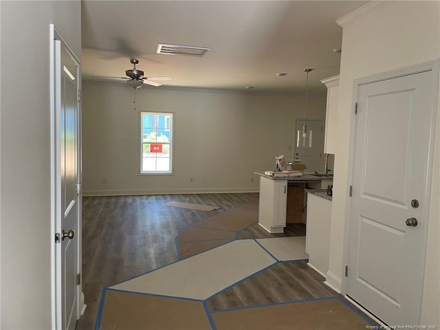 kitchen featuring a ceiling fan, dark wood-type flooring, baseboards, pendant lighting, and ornamental molding