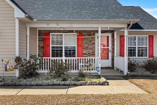 property entrance featuring a porch, stone siding, and a shingled roof