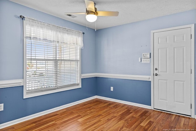 unfurnished room featuring visible vents, baseboards, wood finished floors, a textured ceiling, and a ceiling fan