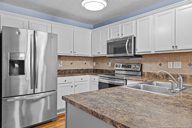 kitchen featuring dark countertops, tasteful backsplash, appliances with stainless steel finishes, and a sink