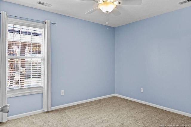 carpeted empty room with visible vents, baseboards, and ceiling fan