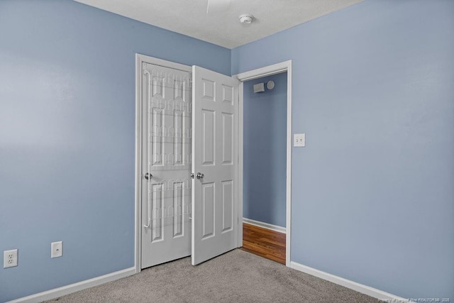 unfurnished bedroom with a closet, carpet flooring, and baseboards