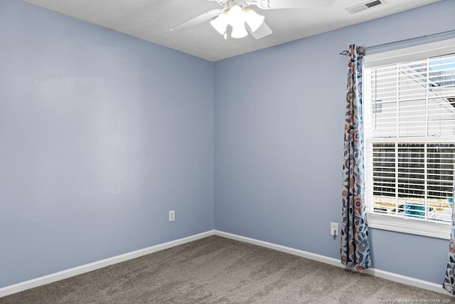 carpeted spare room featuring baseboards, visible vents, a wealth of natural light, and ceiling fan