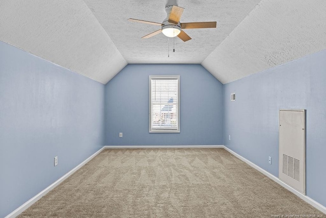 bonus room featuring baseboards, lofted ceiling, ceiling fan, a textured ceiling, and carpet flooring