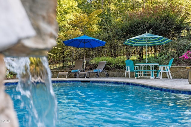 outdoor pool featuring fence and a patio area