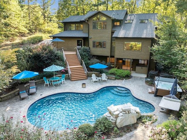 rear view of property featuring stairway, a patio area, an outdoor pool, and roof with shingles