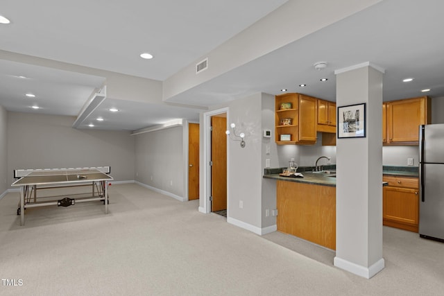 kitchen with brown cabinetry, visible vents, freestanding refrigerator, light carpet, and dark countertops