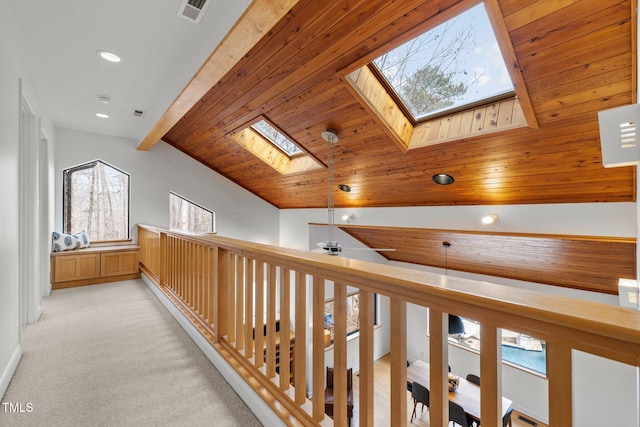 hallway with visible vents, light carpet, lofted ceiling with skylight, recessed lighting, and wooden ceiling