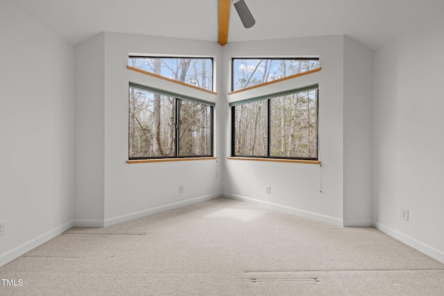 carpeted spare room with a ceiling fan and baseboards