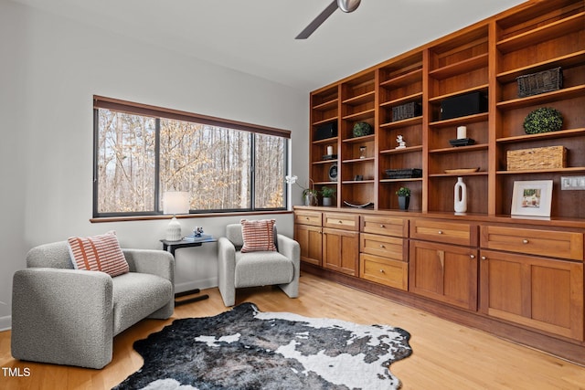 living area with light wood-style floors and a ceiling fan