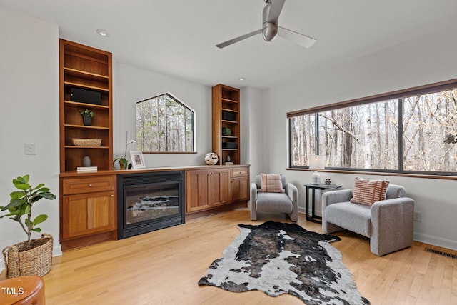 living area with visible vents, a healthy amount of sunlight, ceiling fan, and light wood finished floors