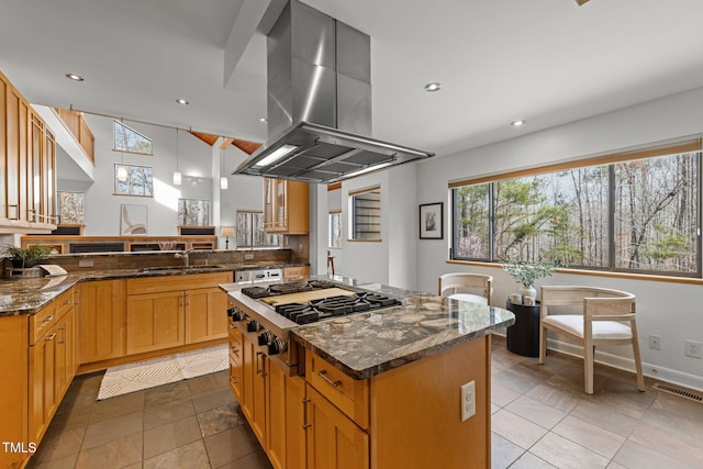 kitchen featuring visible vents, a sink, a center island, stainless steel gas stovetop, and island range hood