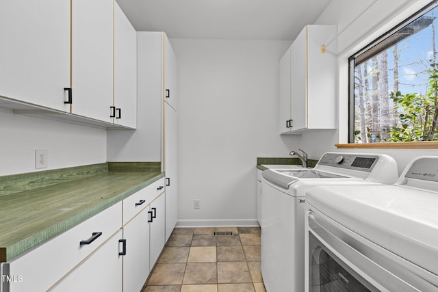 clothes washing area with visible vents, a sink, washing machine and dryer, cabinet space, and baseboards