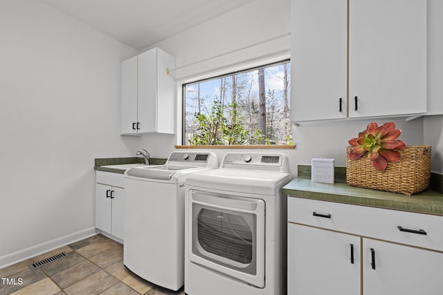 laundry area featuring baseboards, visible vents, cabinet space, a sink, and washer and clothes dryer