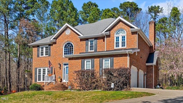 view of front of house with brick siding, an attached garage, a front yard, a chimney, and driveway