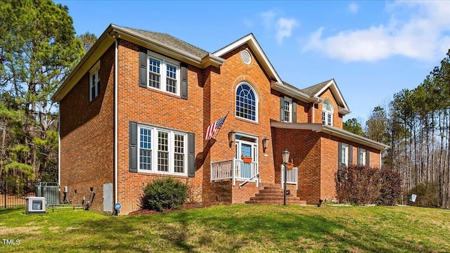 traditional-style home featuring a front lawn, fence, and brick siding