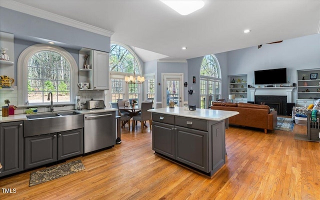 kitchen featuring open shelves, a fireplace, gray cabinets, a sink, and stainless steel dishwasher